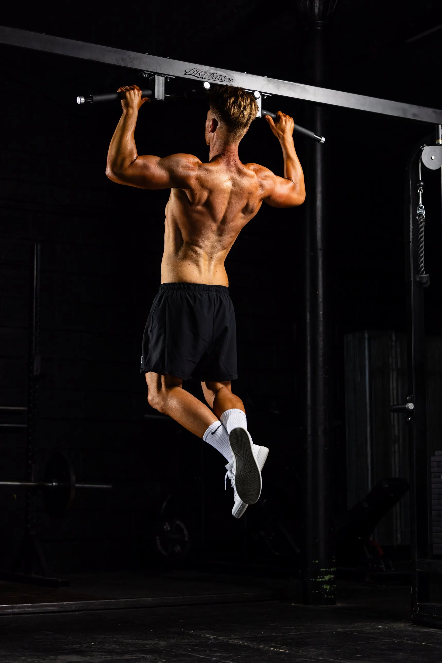 Tom doing a pull-up, seen from behind, at his 2026 photoshoot